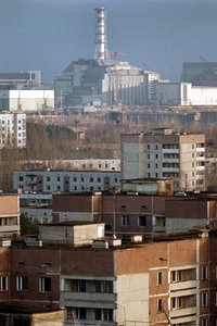 Die leerstehenden Wohnhäuser in der nahen Umgebung des Unglücksreaktors Tschernobyl. Im Hintergrund ist der einbetonierte Reaktor zu sehen, ein Schornstein ragt in den Himmel