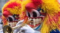 Mit rot-gelben Perücken und Masken verkleidete Trompeter.