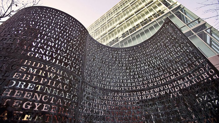 Blick auf eine Skulptur, aus der zahlreiche Buchstaben herausgeschnitten sind
